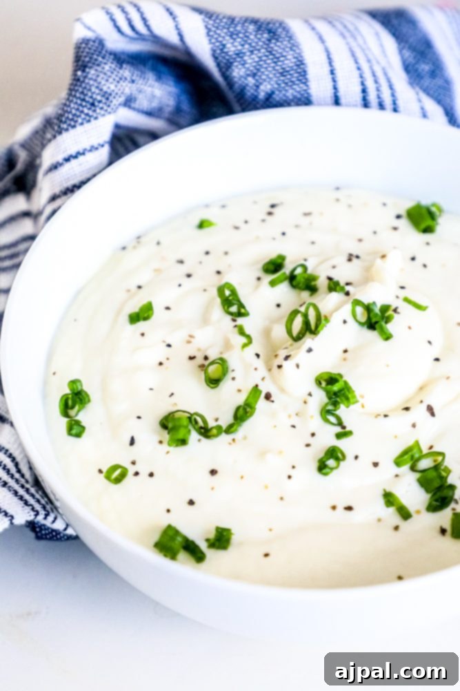 A beautifully presented bowl of creamy mashed cauliflower, garnished with fresh chives, a perfect keto side dish.