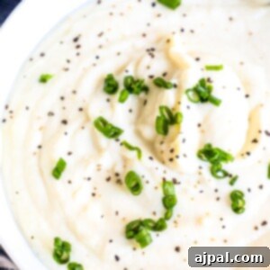 Whipped cauliflower with chives in a white bowl.