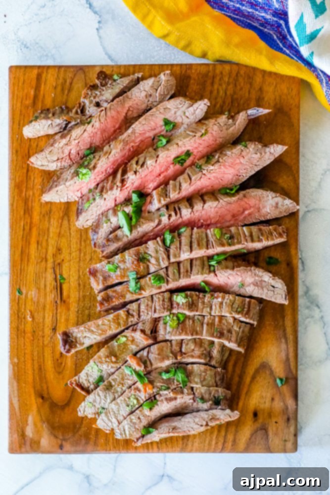 Perfectly Tender Oven Flank Steak 2 Keto-friendly flank steak recipe with garlic butter, served on a wooden cutting board.