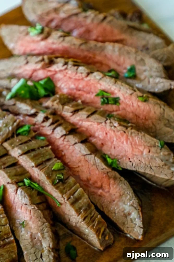 Perfectly Tender Oven Flank Steak 5 Grilled steak on a wooden cutting board using the garlic butter roasted flank steak recipe.