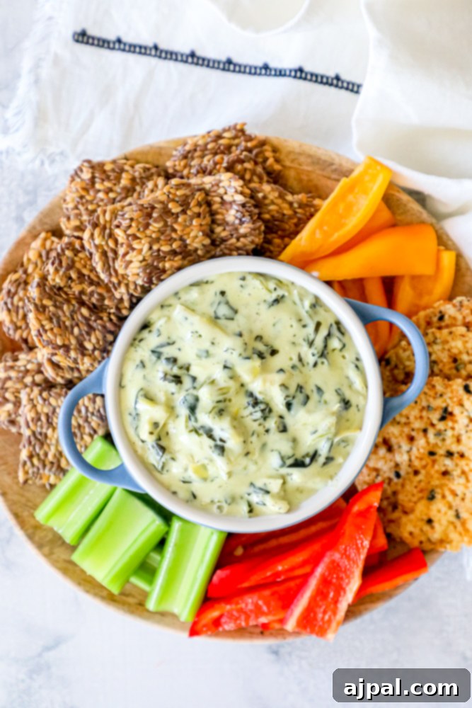 A close-up of a plate featuring a generous dollop of creamy spinach dip, perfectly complemented by a variety of crisp, colorful vegetables, highlighting its appealing texture and freshness.