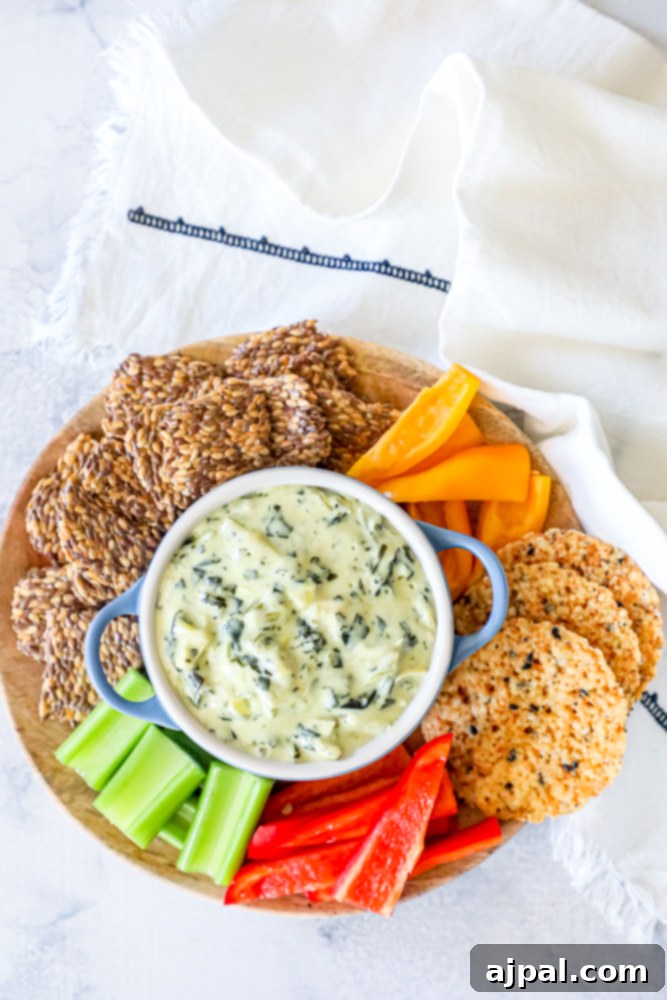 A tantalizing plate featuring creamy spinach and artichoke dip generously spread on crisp keto crackers, highlighting a delicious and low-carb snack or appetizer option.