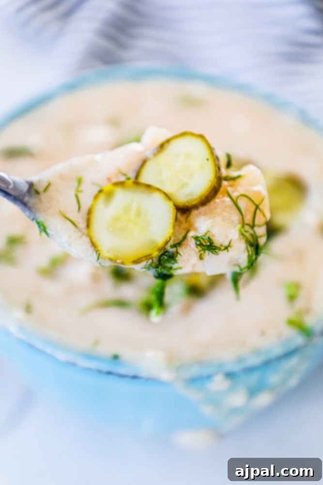 Simple Dill Pickle Soup 6 A charming rustic bowl brimming with creamy dill pickle soup, elegantly garnished with fresh dill sprigs and delicate pickle slices, ready for a comforting meal.