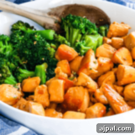 Teriyaki Chicken and broccoli in a white bowl with a wooden spoon.