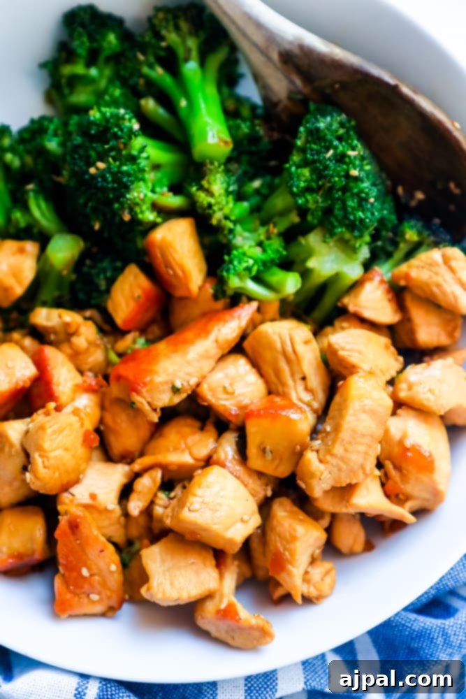 Close-up of Instant Pot Chicken Teriyaki with steamed broccoli, served in a white bowl with a wooden spoon.