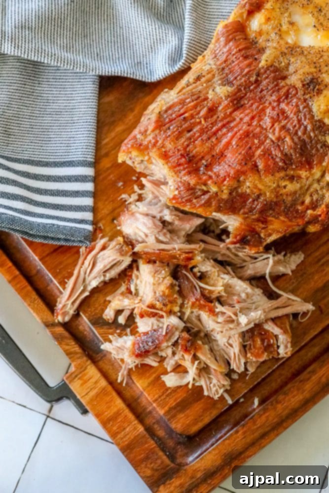 Ultimate Crispy Baked Pork Shoulder 2 Pulled pork with crunchy skin shredded on a cutting board, ready to serve.