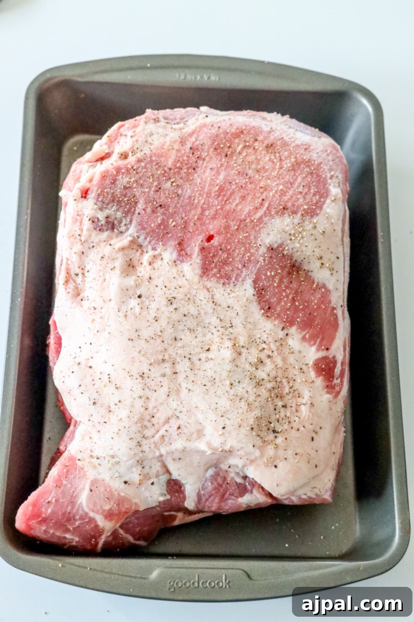 Ultimate Crispy Baked Pork Shoulder 4 Seasoned raw pork shoulder in a pan, coated with spices.