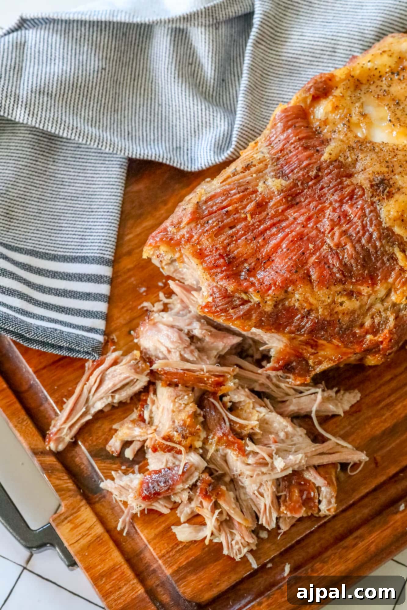 Ultimate Crispy Baked Pork Shoulder 7 A savory pulled pork on a rustic wooden cutting board, showcasing its crispy texture.