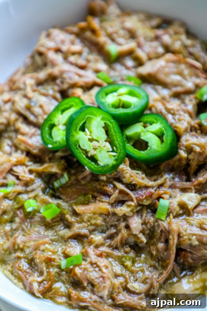 Zesty Green Chile Pork Carnitas 3 Delicious pulled pork in a white bowl, generously topped with fresh jalapeños and rich green chile sauce.