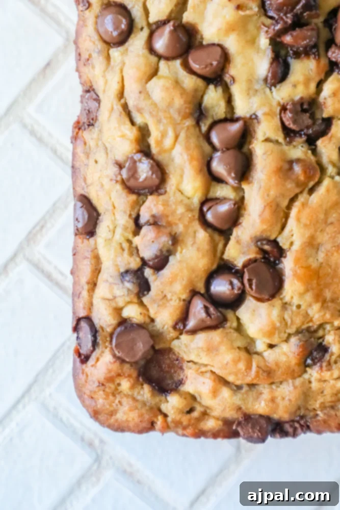 Closeup picture of a slice of chocolate chip banana bread with a golden-brown crust and visible chocolate chips