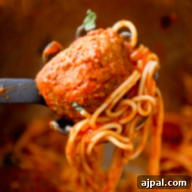 A fork is being used to scoop the best instant pot spaghetti and meatballs out of a pot, showcasing a delicious meal.