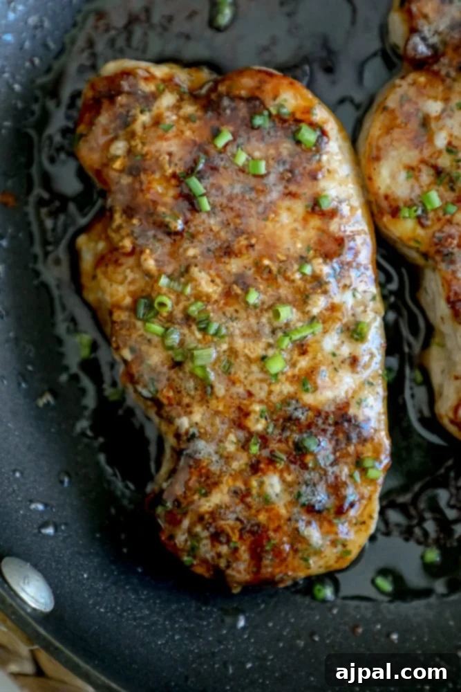 Golden-brown ranch pork chops garnished with fresh chives, served in a cast iron skillet.