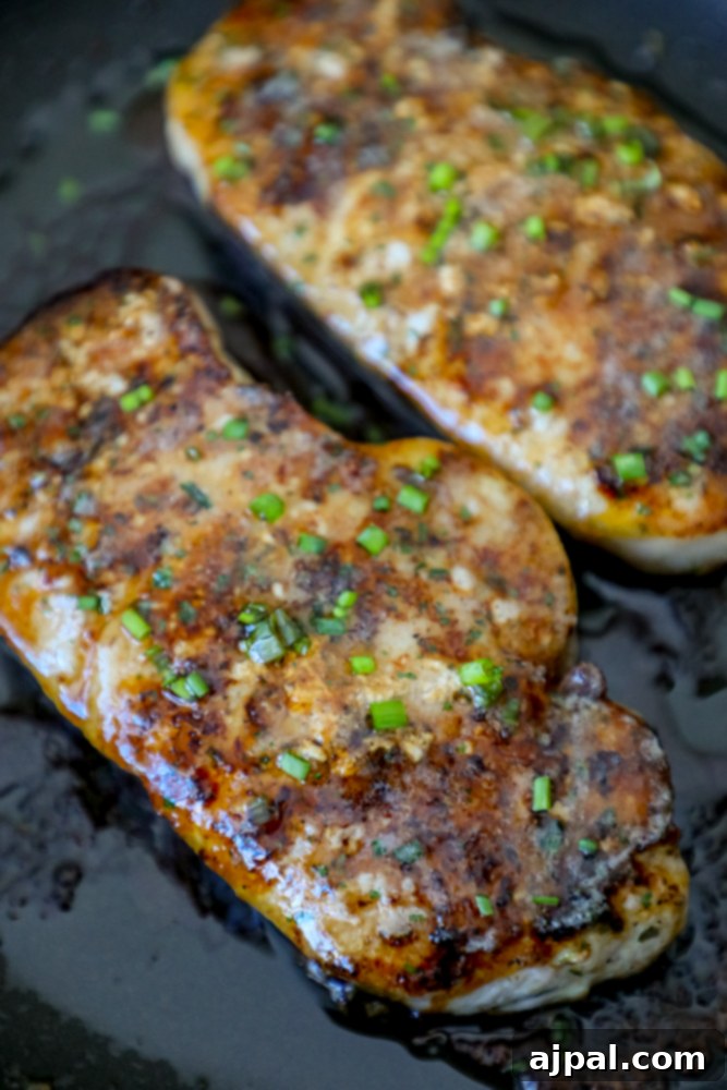 Close-up of baked ranch pork chops, seasoned and ready to be served, in a skillet.