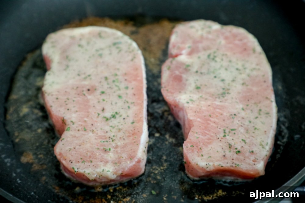 Ranch seasoned pork chops sizzling in a hot cast iron pan, achieving a perfect sear.
