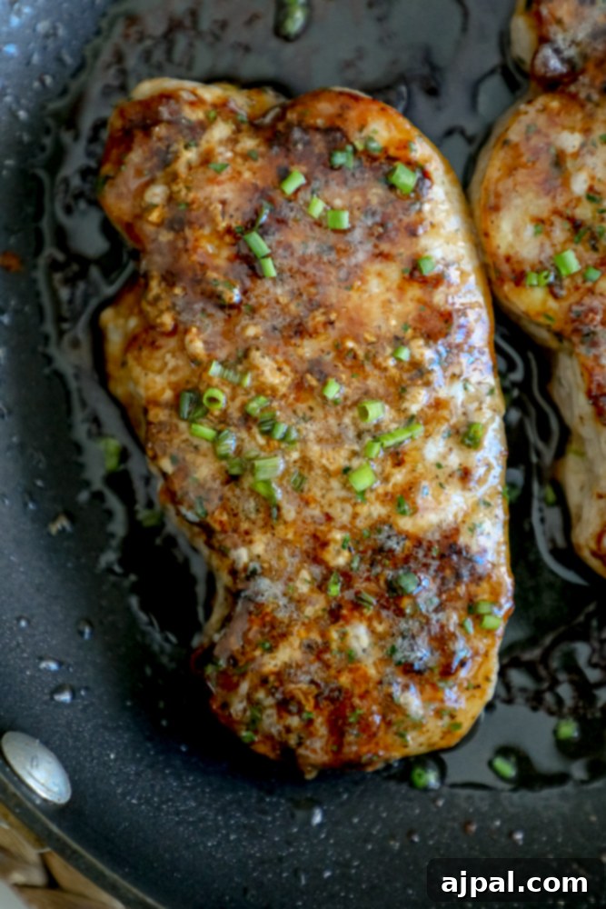 A single baked ranch pork chop, topped with green onions, presented in a black skillet.