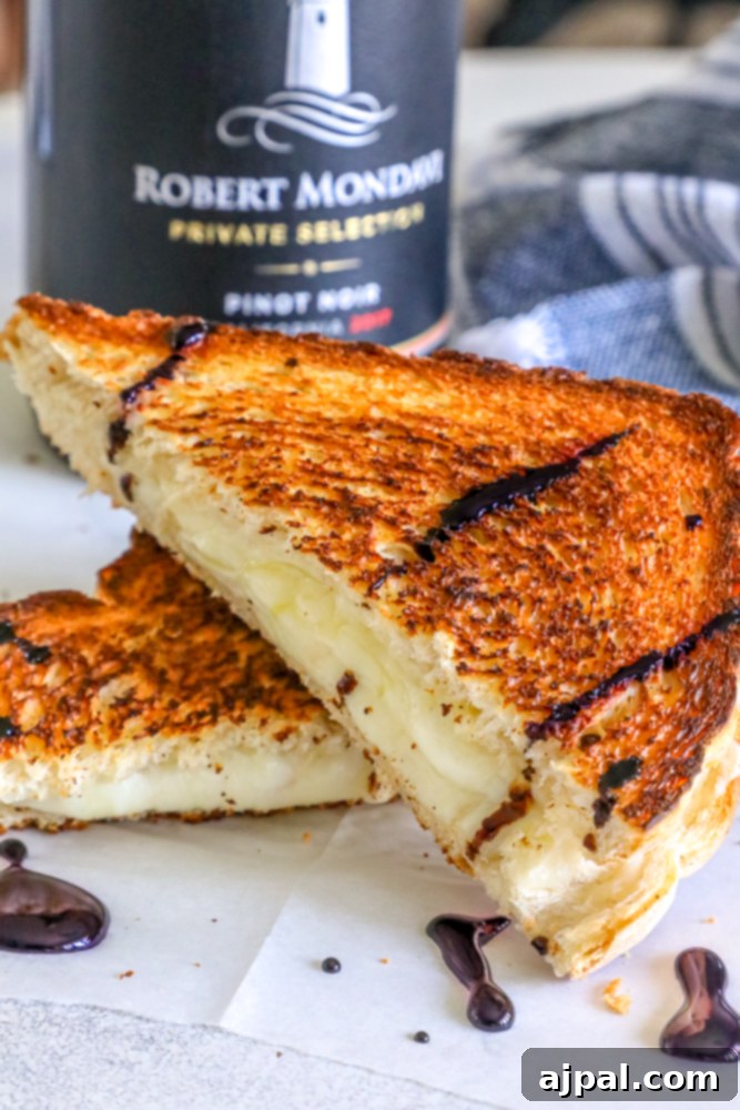 A bottle of red wine stands next to a perfectly cooked gourmet grilled cheese sandwich, highlighting the perfect pairing.