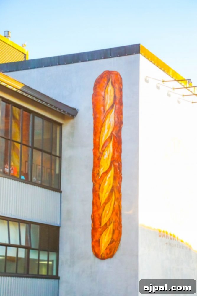 A vibrant mural of a baguette painted on a building in Fisherman's Wharf, San Francisco, highlighting the city's famous sourdough bread culture.