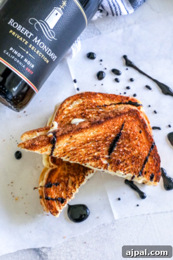 A wine bottle and a gourmet grilled cheese sandwich with a side of rich red wine sauce, ready for an indulgent meal.
