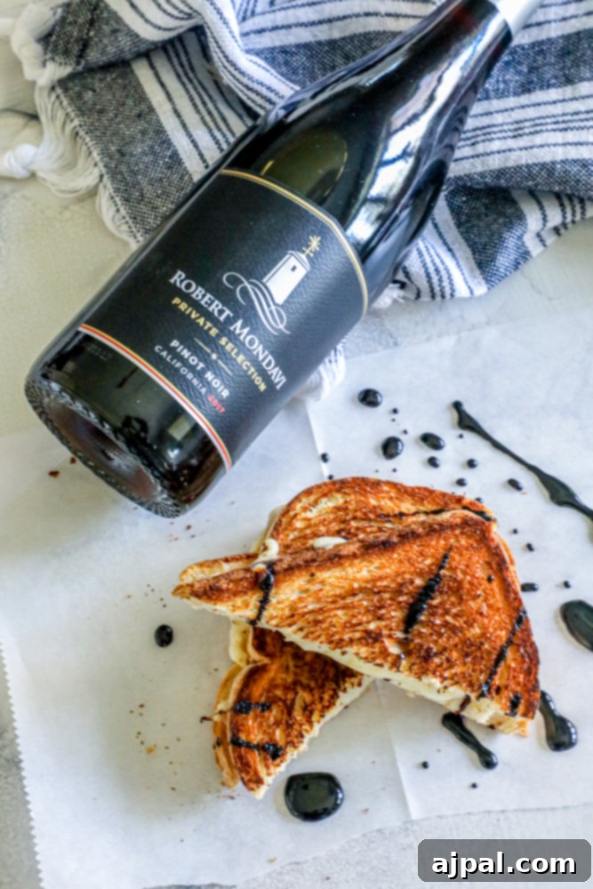 A delectable grilled cheese sandwich, cut in half, presented alongside a glass of red wine, highlighting a sophisticated culinary pairing.