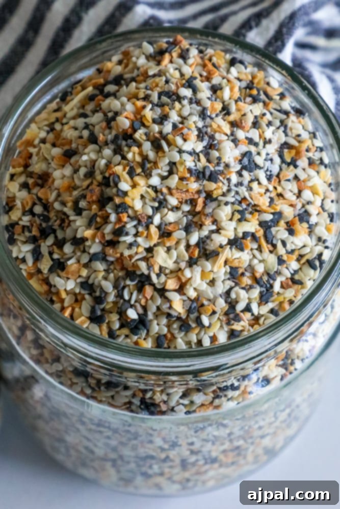 Ultimate Everything Bagel Seasoning Blend 4 A glass jar filled with sesame seeds, poppy seeds, and spices, demonstrating the finished everything bagel seasoning mix.