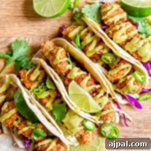 Four pan fried chicken tacos with lime and cilantro on a wooden cutting board.