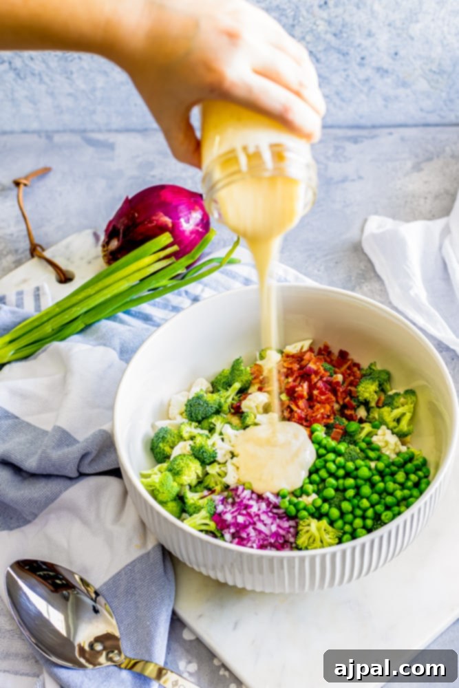 hand pouring creamy dressing into bowl of broccoli salad