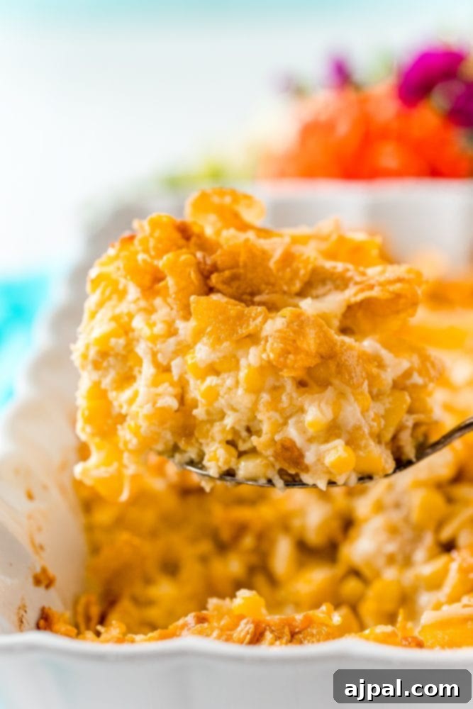 Golden Scalloped Corn Bake 10 scalloped corn casserole on a spoon over a casserole dish with baked scalloped corn