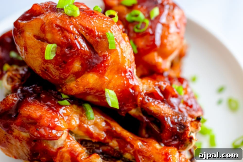 Deliciously cooked BBQ chicken legs on a white plate, garnished with fresh green onions, ready to be served.