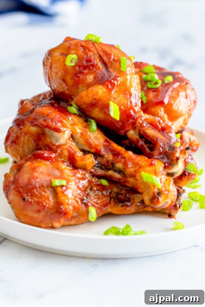 Perfectly cooked Instant Pot BBQ chicken legs, garnished with fresh green onions, on a pristine white plate.