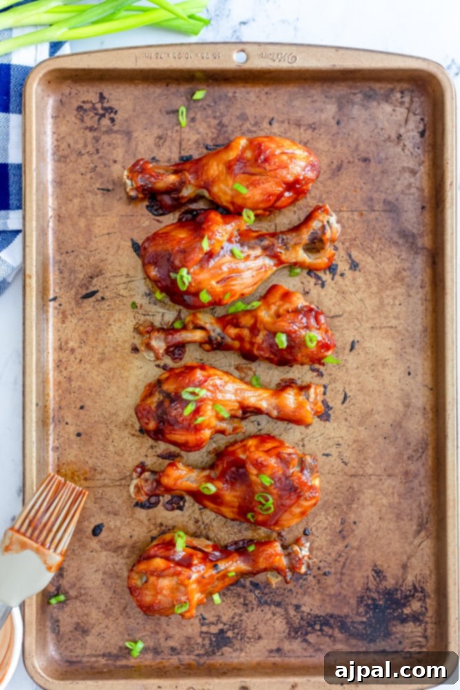 Chicken drumsticks generously basted with BBQ sauce, ready for broiling to achieve a sticky, caramelized glaze.