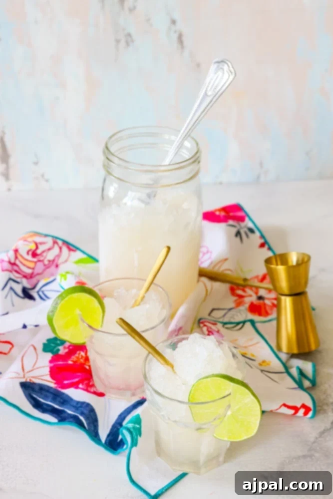 A jar of a frosty gin and tonic slush, infused with lime slices, served with a gold spoon, evoking a sense of refreshing relaxation.