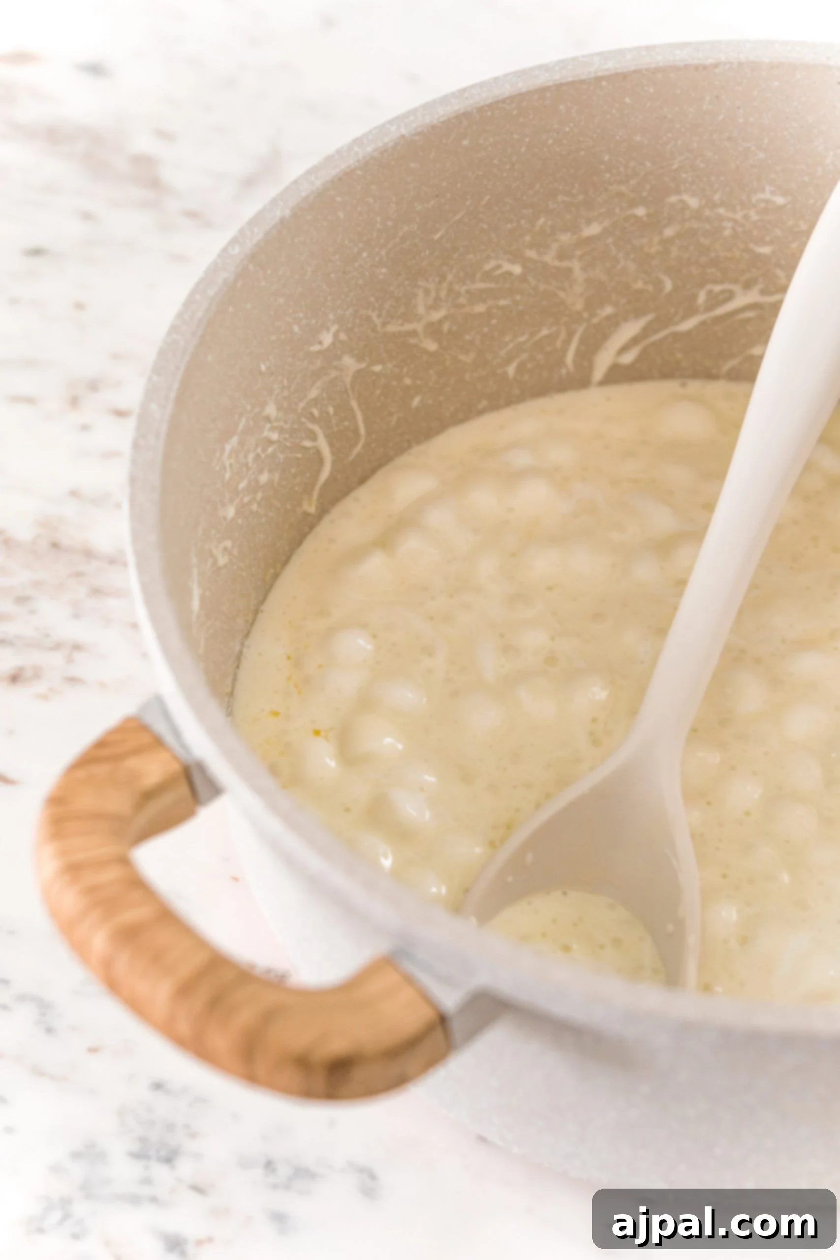 A close-up shot of butter and mini marshmallows slowly melting together in a large saucepan over gentle heat, forming a smooth, golden mixture.