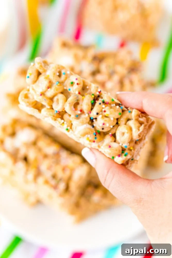 A hand holding a Cheerio bar with sprinkles on it, highlighting the fun and colorful topping.
