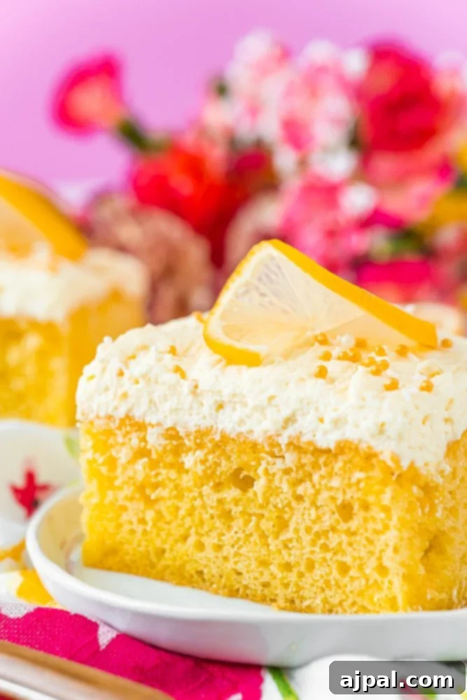 A slice of Lemon Jello Poke Cake with visible Jello-infused pockets, presented on a plate for a refreshing dessert.