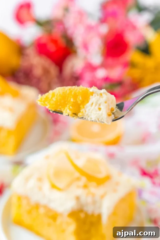 A close-up of a Lemon Poke Cake, richly frosted with creamy lemon topping, showcasing its soft texture.
