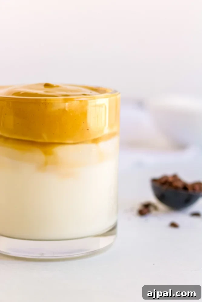 Creamy keto Dalgona coffee with caramel-colored foam, garnished with coffee beans.