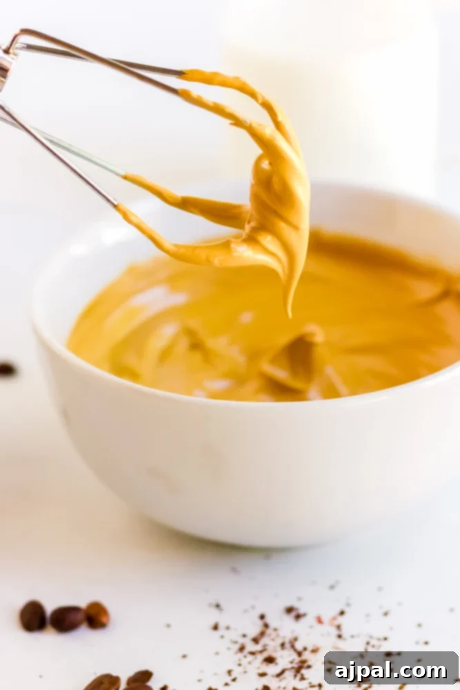 Whipping the coffee mixture in a bowl with an electric whisk.