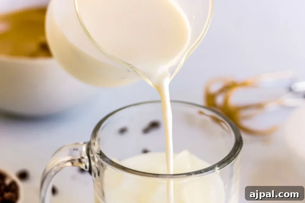 Unsweetened almond milk being poured into a clear mug.