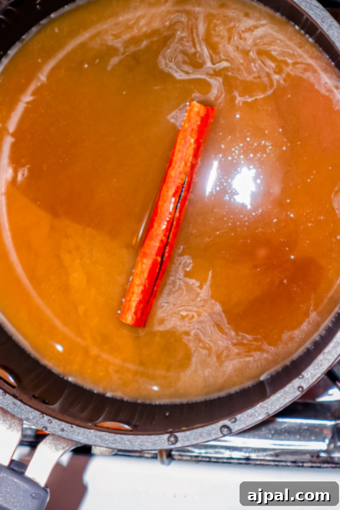 A pot of apple cider with a cinnamon stick in it, simmering to create simple syrup.
