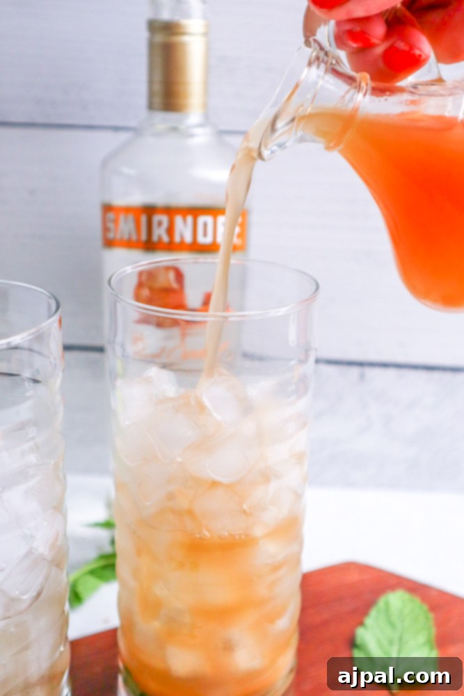 A person mixing an apple mojito cocktail, adding the final ingredients.