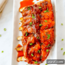 Asian Instant Pot Ribs with sauce and green onions on a white plate.