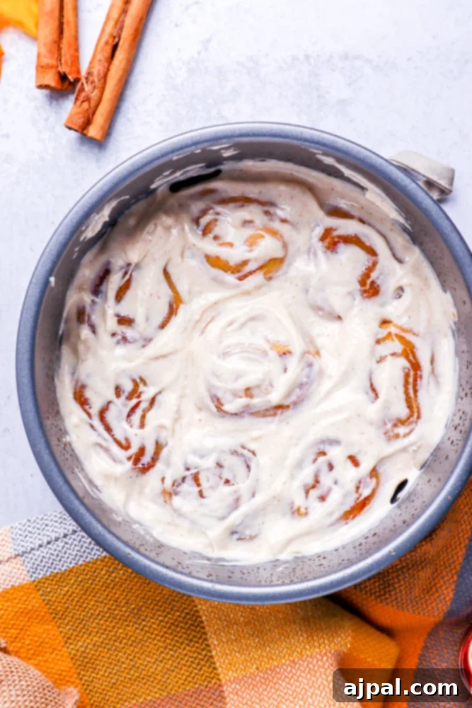 Easy Instant Pot Pumpkin Cinnamon Rolls 19 8 pumpkin cinnamon rolls in a metal cake pan covered with white frosting