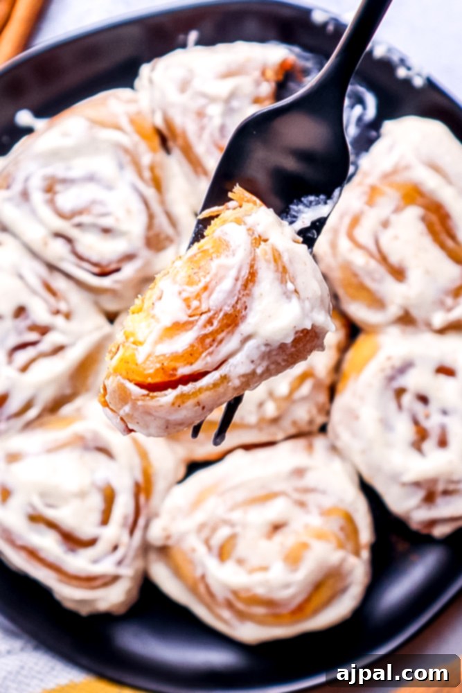 A tantalizing image of a fork piercing a pumpkin cinnamon roll, revealing a delicious bite missing, tempting you to take a taste.