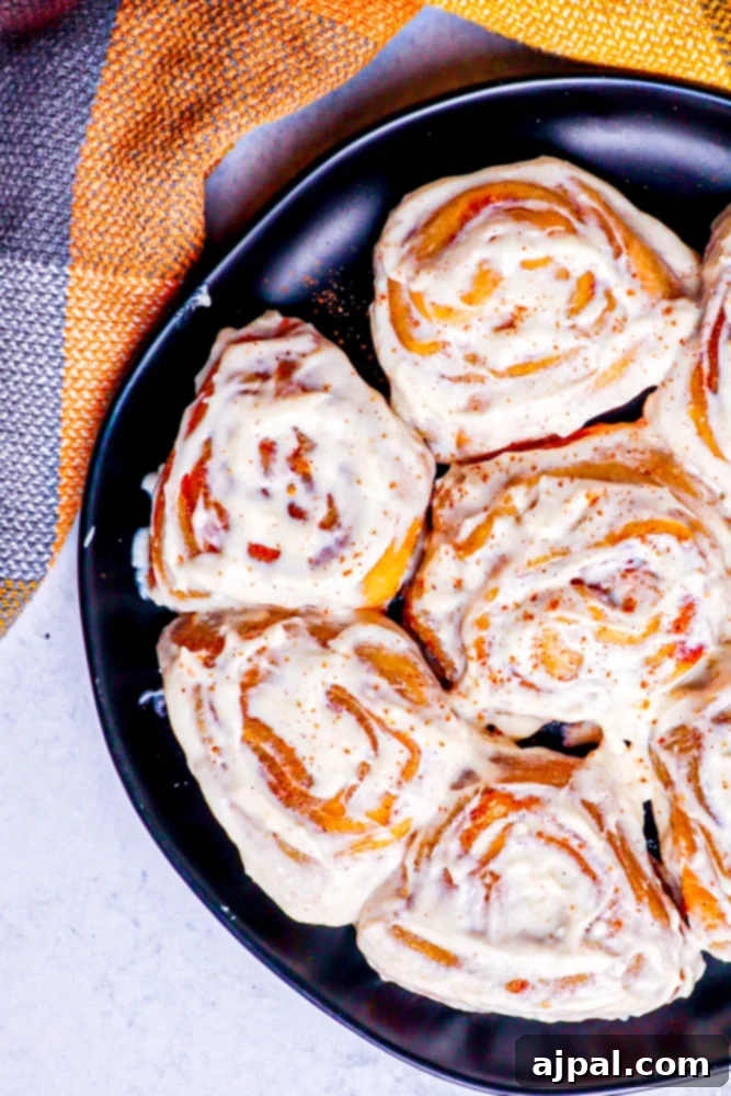 Easy Instant Pot Pumpkin Cinnamon Rolls 5 picture of pumpkin cinnamon rolls on a black plate