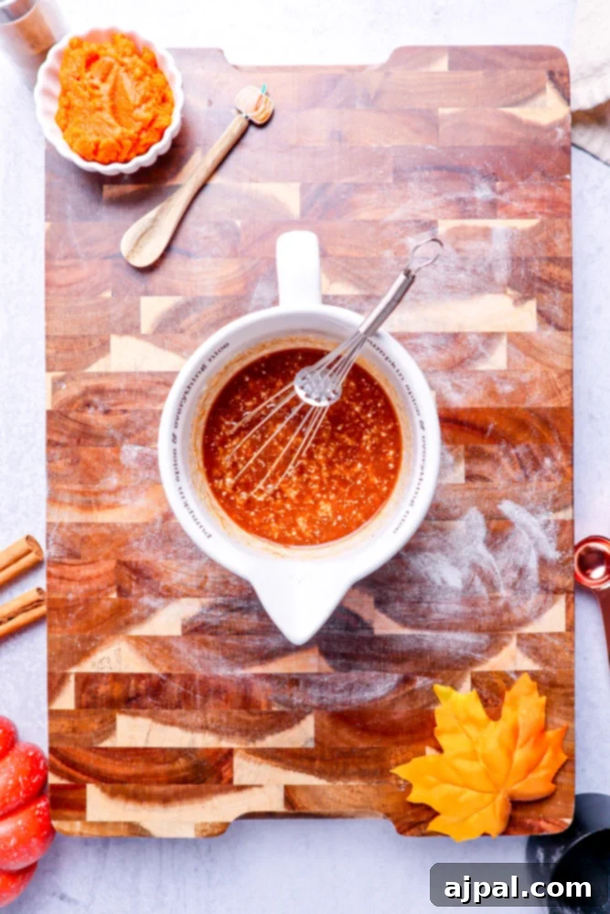 Easy Instant Pot Pumpkin Cinnamon Rolls 8 melted butter with brown sugar in a white measuring cup on a wooden cutting board