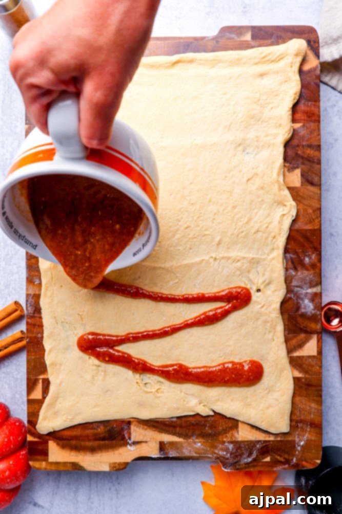 Easy Instant Pot Pumpkin Cinnamon Rolls 10 dough spread flat on a wooden cutting board with brown butter and spice mixture being poured on it.