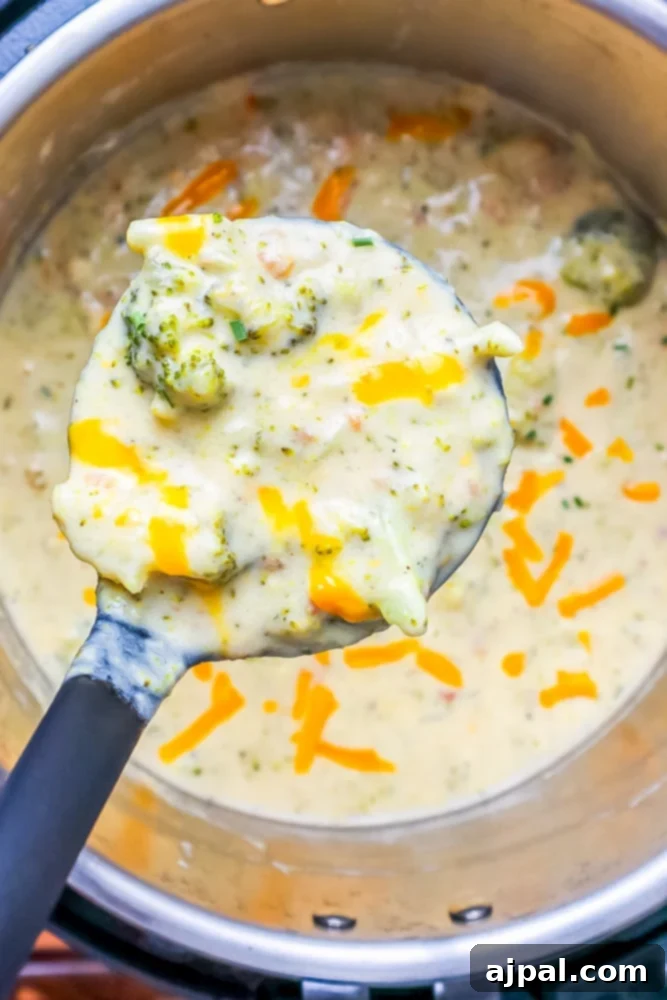 Creamy Instant Pot Keto Broccoli Cheddar Soup 2 A spoon scooping creamy keto broccoli cheddar soup from a bowl with an Instant Pot in the background, showcasing its rich texture.