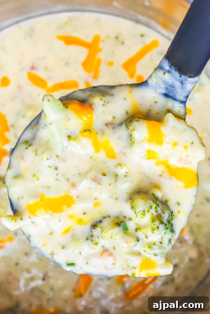 Creamy Instant Pot Keto Broccoli Cheddar Soup 12 A ladle gracefully holds a portion of creamy keto broccoli cheddar soup above an Instant Pot, highlighting its delicious texture and readiness to serve.