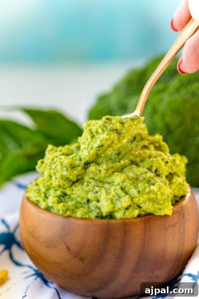 Easy and Delicious Broccoli Pesto 2 Green pesto in a wooden bowl with a spoon, showcasing a delicious recipe for broccoli pesto.