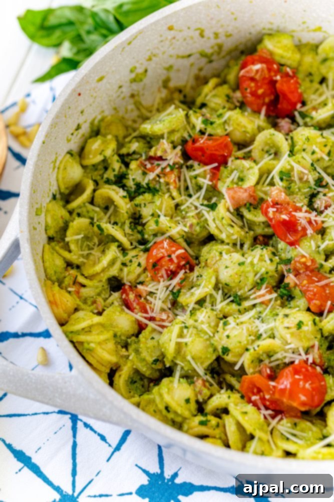 Easy and Delicious Broccoli Pesto 10 Pasta with broccoli pesto over it, tomatoes, and parmesan, cooked in a skillet.